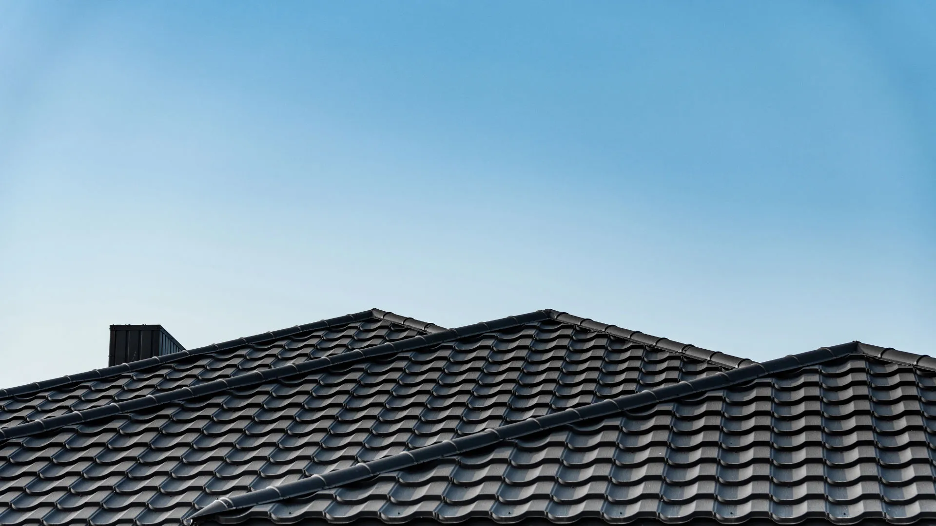 Une toiture en tuiles noires avec un ciel bleu